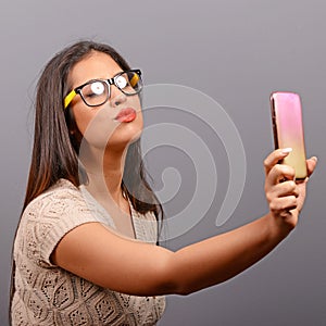Portrait of a girl taking selfie with cellphone against gray background