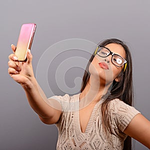 Portrait of a girl taking selfie with cellphone against gray background