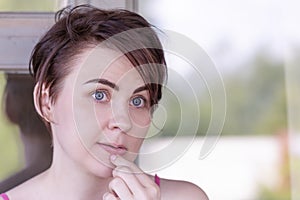 Portrait of a girl, thoughtfully touching her hand to her lips