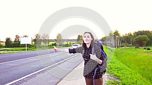 Portrait of a girl tourist with a backpack on the highway ,hitching a ride,thumb up