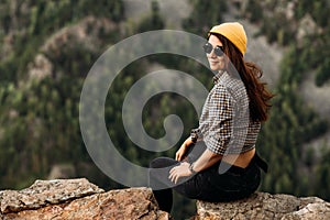 Portrait of a girl traveler in a yellow cap on the background of mountains. Portrait of a female tourist.