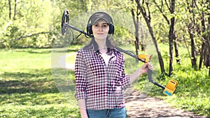 Portrait of a girl treasure hunter with a metal detector, looking at camera