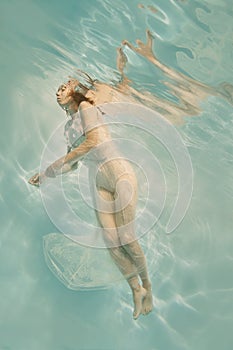 Portrait of a girl underwater in a white lace dress