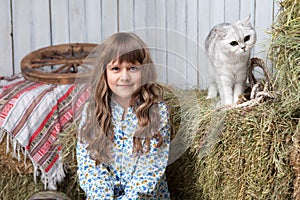 Portrait girl villager, cat on hay stack in barn photo