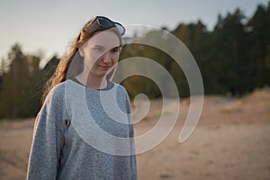 Portrait of girl in warm pullover walking on a beach during sunset