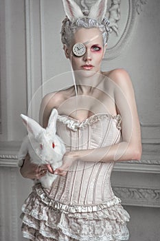 Portrait of a girl in a whight costume holding a white bunny