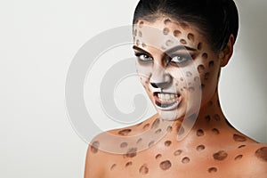 Portrait of a girl on a white background. . face art. body art. hairstyle. black hair. wild cat. growl. snarl