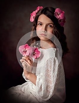Portrait of a girl in a white dress, she holds branches of pink orchid flowers in her hands.