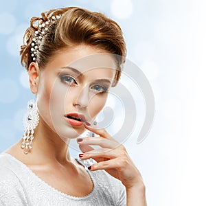 Portrait of a girl in a white dress and jewelery on a blue background.