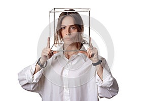 Portrait of a girl in a white shirt with a metal cube-cage on his head. isolate. The concept of estrangement, the man in a case