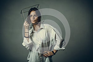 Portrait of a girl in a white shirt with a metal cube-cage on his head. isolate. The concept of estrangement, the man in a case