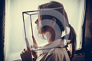 Portrait of a girl in a white shirt with a metal cube-cage on his head. isolate. The concept of estrangement, the man in a case