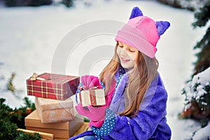 Portrait of girl in winter forest. Girl carries a Christmas tree and presents with sled.