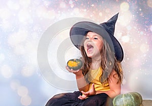 Portrait of girl in the witch hat with pumpkin