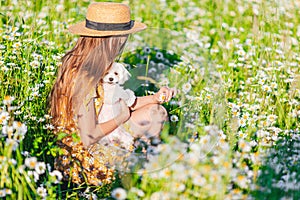 Portrait of girl in a yellow dress and straw hat on a chamomile field in summer