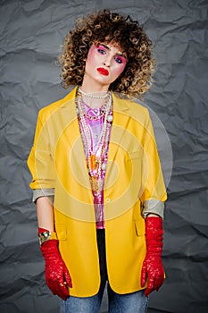 Portrait of a girl in a yellow jacket and blue jeans with afro hair of the eighties, disco era.