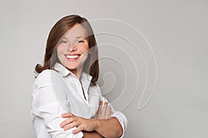 Portrait of glad smiling happy doctor in white coat uniform standing with crossed hands on grey wall background