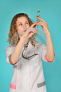 portrait of a glamorous female doctor with a syringe. turquoise background.