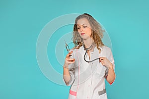 portrait of a glamorous female doctor with a syringe. turquoise background.