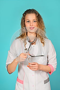 portrait of a glamorous female doctor with a syringe. turquoise background.