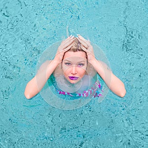 Portrait of a glamorous girl in a swimming pool. Lipstick in purple. View from above.