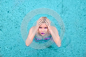 Portrait of a glamorous girl in a swimming pool. Lipstick in purple. View from above.