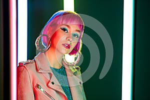 Portrait of glamorous woman with dyed pink hairstyle under neon light. Nightclub, trendy outfit. Teenager, zoomer Z