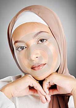 Portrait of a glowing beautiful muslim woman isolated against grey studio background. Young woman wearing a hijab or