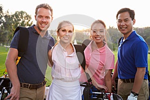 Portrait Of Golfers Walking Along Fairway Carrying Golf Bags