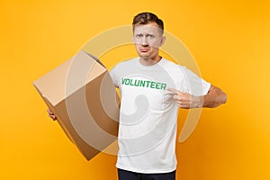 Portrait of good kind man in white t-shirt with written inscription green title volunteer with big cardboard box