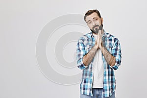 Portrait of good-looking caucasian bearded man with begging gesture, asking for forgiveness or favor while looking at