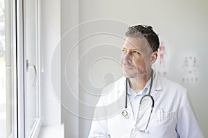 Portrait of a good looking male doctor in his office with a three-day beard and white coat