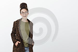 Portrait of good-looking stylish european woman with curly hair and bun haircut, wearing black trendy glasses and