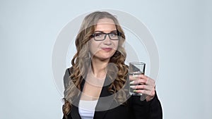 Portrait of good-looking woman being drinking mineral water from transparent glass feeling healthy, slow motion