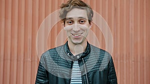 Portrait of good-looking young man making eyes and smiling looking at camera outdoors