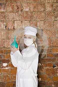 Portrait of a good looking young nurse with enema in her arms in a brick red background. Medical concept.