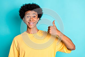 Portrait of good mood man with afro hairstyle wear oversize t-shirt showing thumb up approve nice job isolated on teal