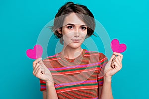 Portrait of gorgeous adorable girl with short hair wear stylish t-shirt showing two pink hearts in arms isolated on teal