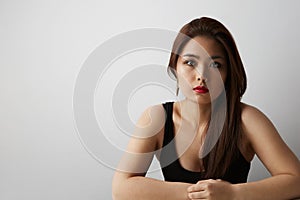 Portrait of gorgeous asian woman with long dark hair looking at camera, isolated over white background in studio