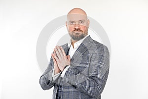 Portrait of gorgeous bearded middle-aged businessman in grey checkered jacket, vest, white shirt, stand folding hands.