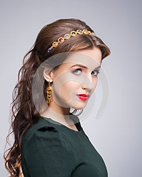 Portrait of gorgeous brunette wearing luxury golden coronet and earrings