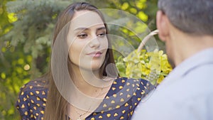 Portrait of gorgeous Caucasian young woman talking with boyfriend on summer day outdoors and smiling. Close-up of happy