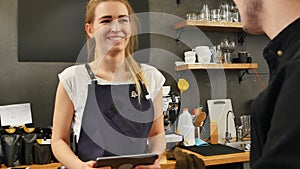 Portrait of a gorgeous female barista taking the order of a customer with a tablet computer and smiling