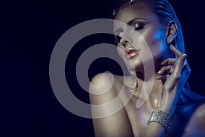 Portrait of gorgeous glam blond woman with wet hair, artistic glittering make-up and naked shoulders touching her neck