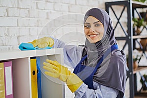 Portrait of a gorgeous Muslim woman cleaning shelves with books