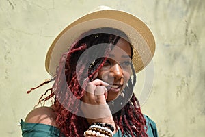 Portrait of a gorgeous plus-sized woman of color on her phone while wearing a sun hat