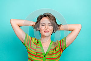 Portrait of gorgeous positive girl closed eyes arms behind head isolated on teal color background