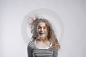 Portrait of a gorgeous teenage girl with curly hair, blowing in wind. Studio shot, white background with copy space