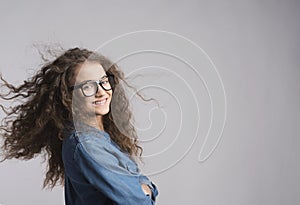 Portrait of a gorgeous teenage girl with curly hair and eyeglasses. Studio shot, white background with copy space