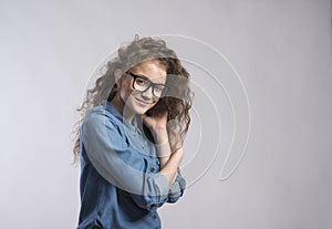 Portrait of a gorgeous teenage girl with curly hair and eyeglasses. Studio shot, white background with copy space